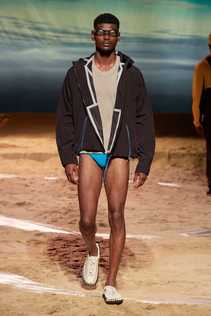 A fitted black neoprene hooded jacket paired with a blue swimsuit.