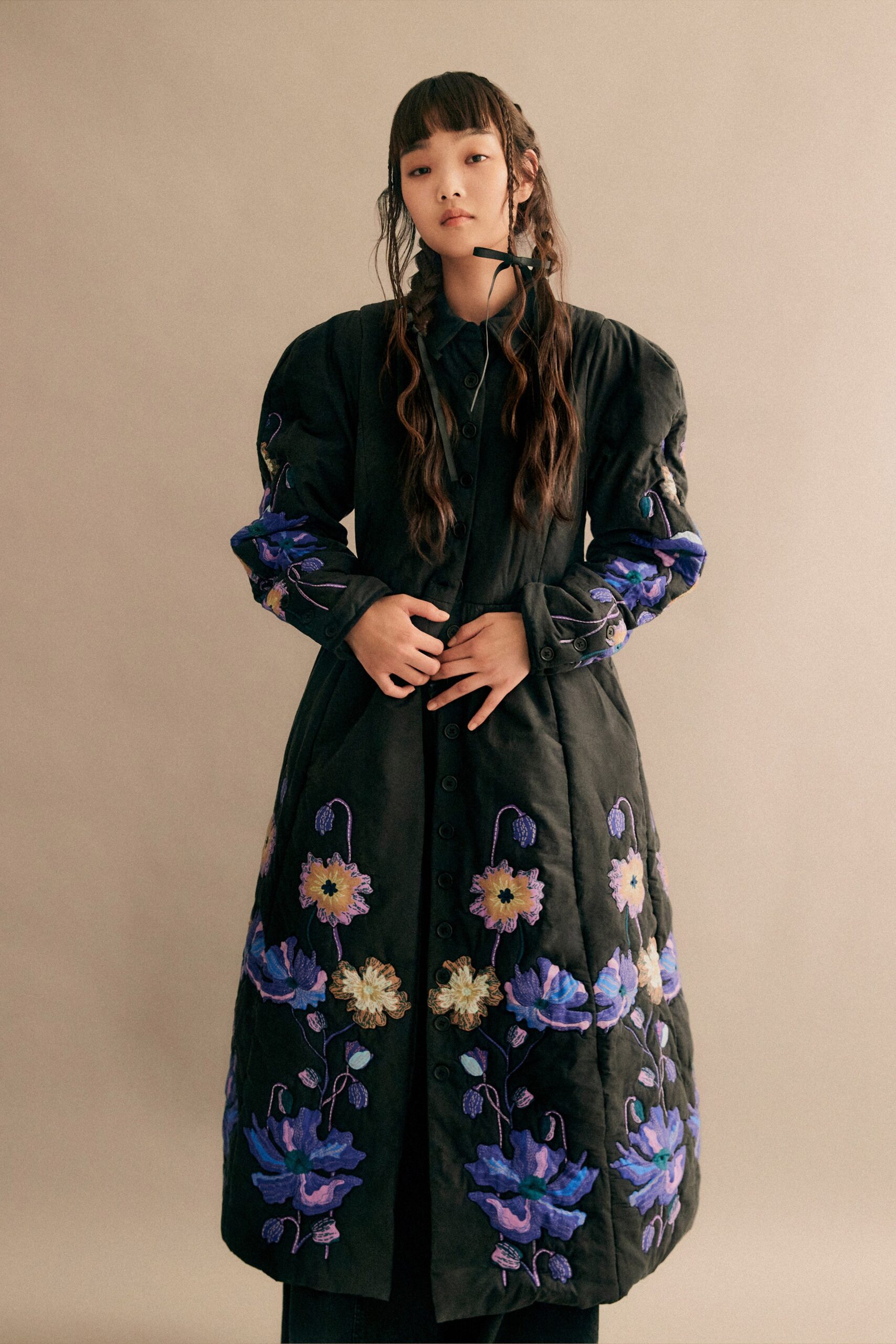 A fitted black dress with long sleeves, a collared neckline, and intricate embroidery.