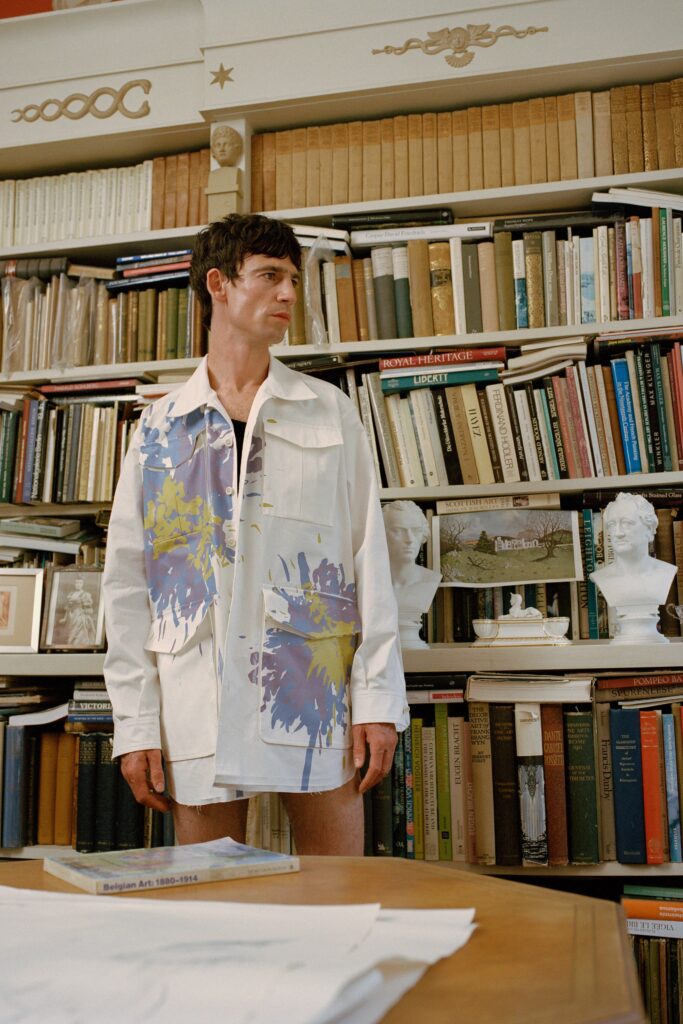 A relaxed white shirt with multicolor prints and long sleeves, featuring a collared design.