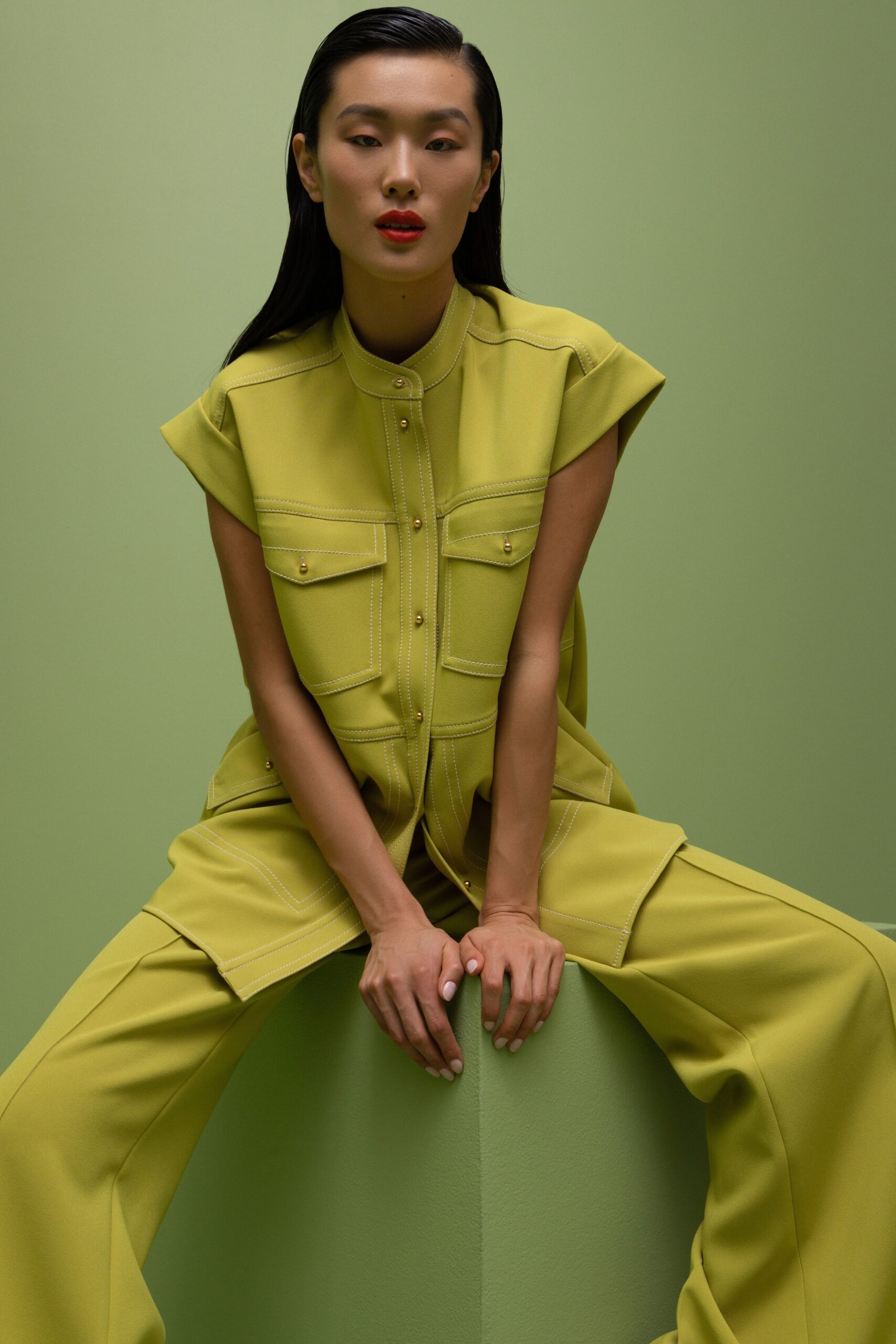 A relaxed green cotton jumpsuit with short sleeves and a collared neckline, featuring button details.