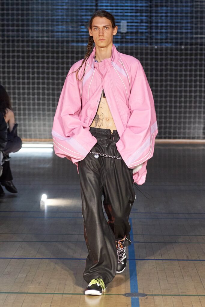 An oversized pink jacket with long sleeves and black leather pants featuring a layered design.