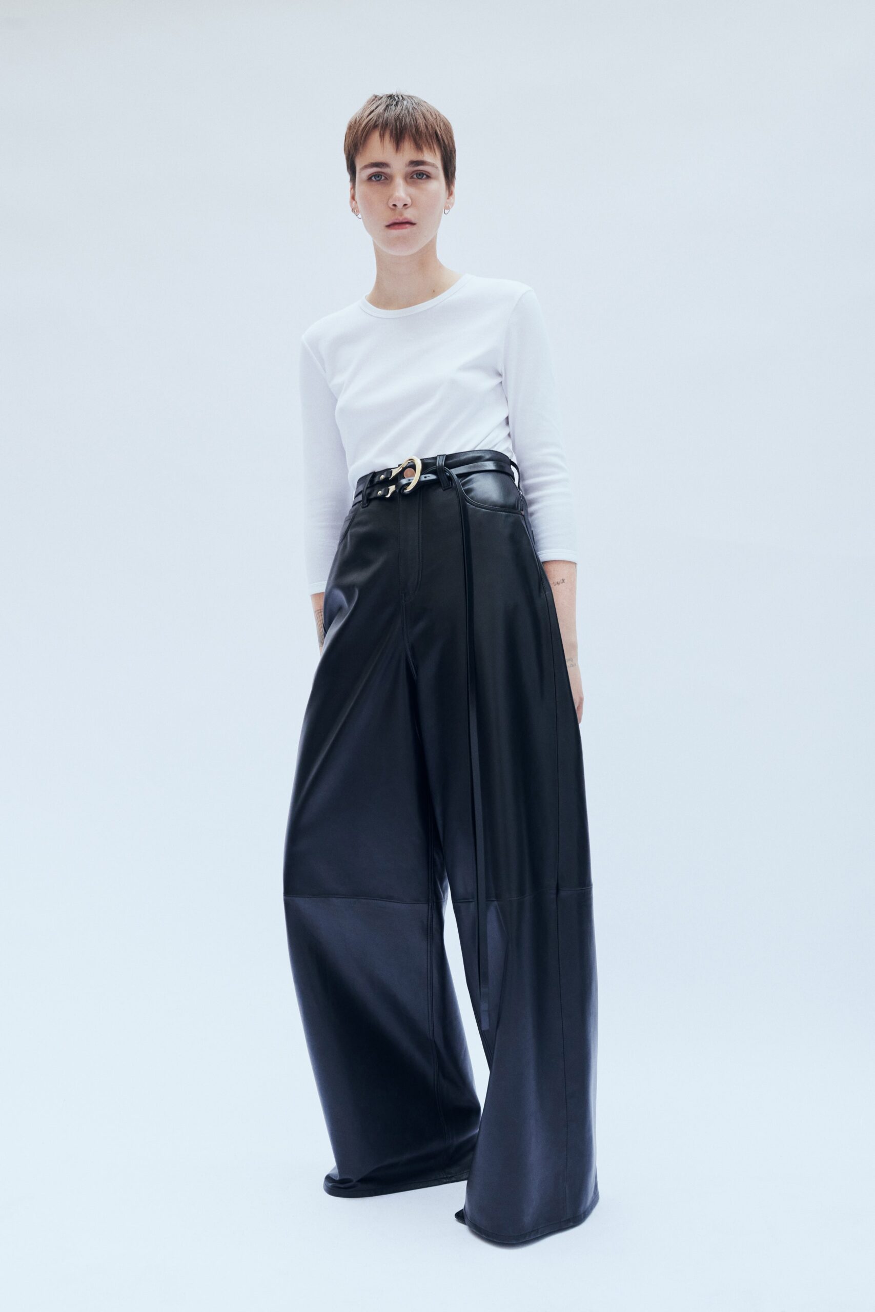 A relaxed fit outfit featuring black leather wide-leg pants paired with a long-sleeve white top.