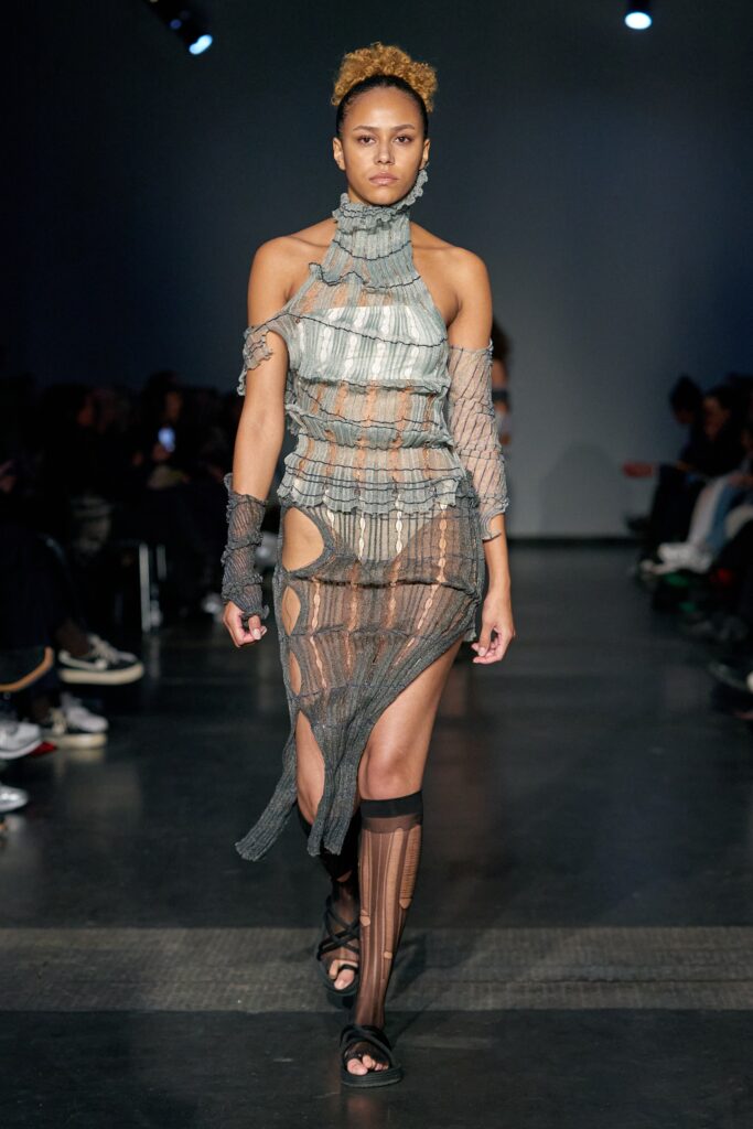 A fitted gray mesh dress with a high neckline and asymmetric cutout details.