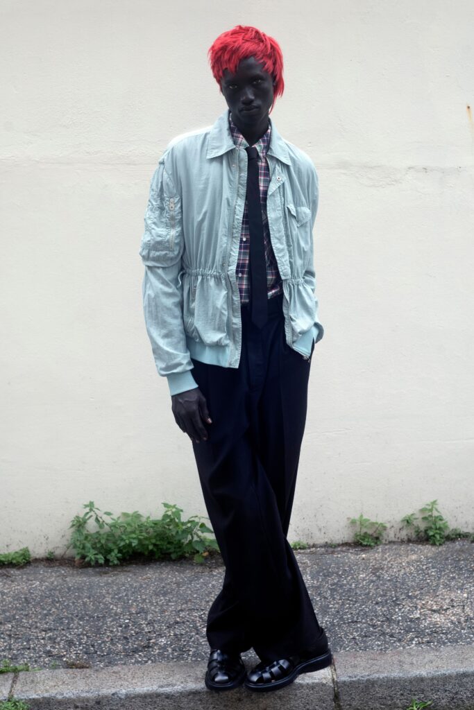 A relaxed light blue jacket with long sleeves paired with wide-leg black pants.