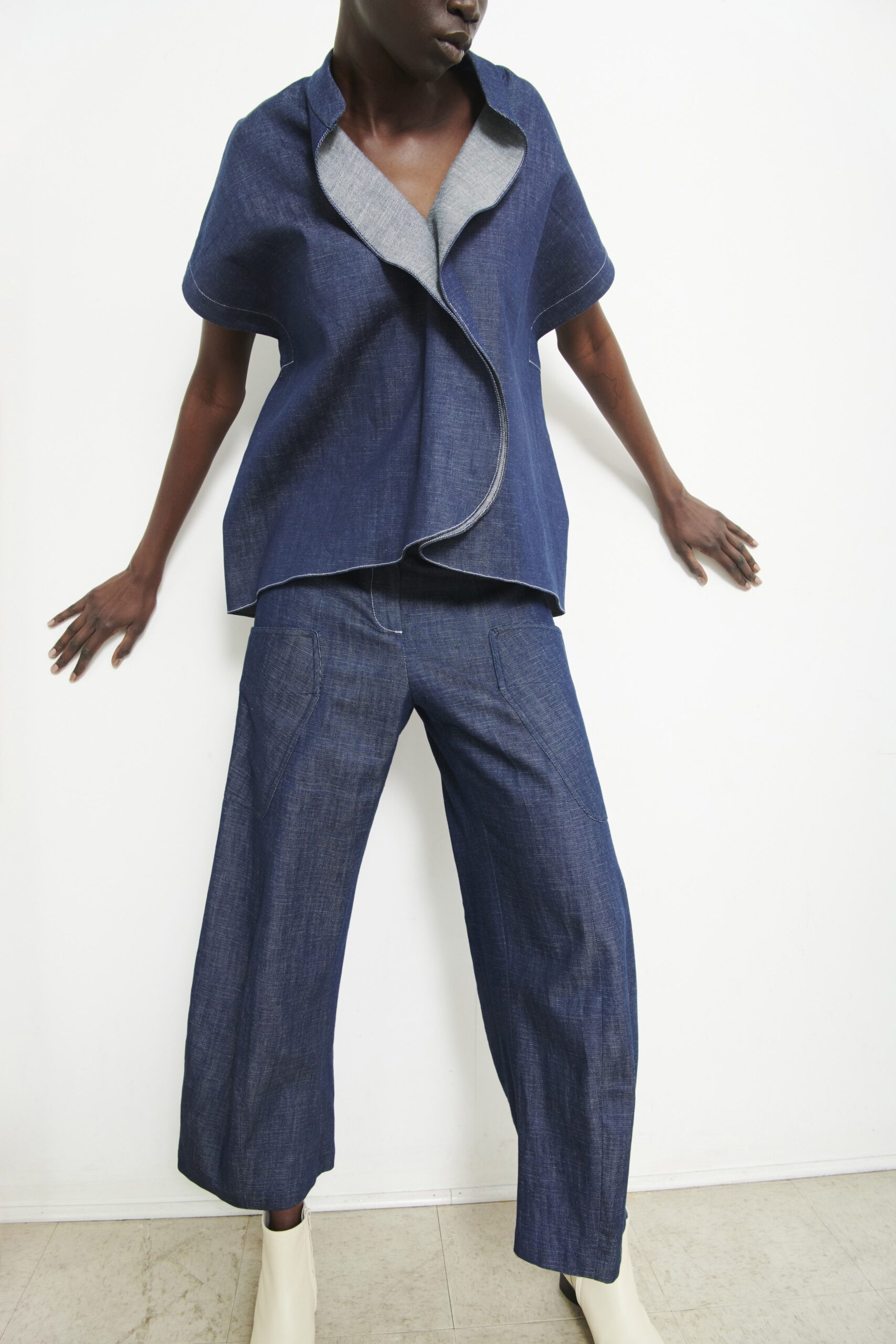 A relaxed blue denim top with short sleeves and asymmetric design paired with matching pants.