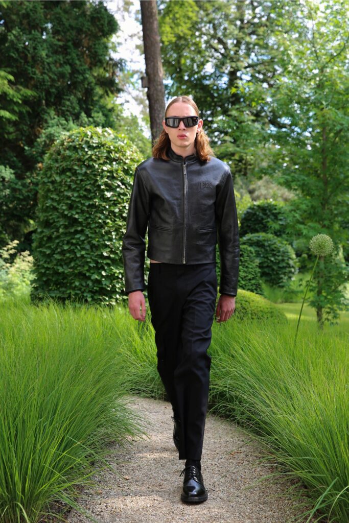A fitted black leather jacket with a zippered front paired with tailored black pants.