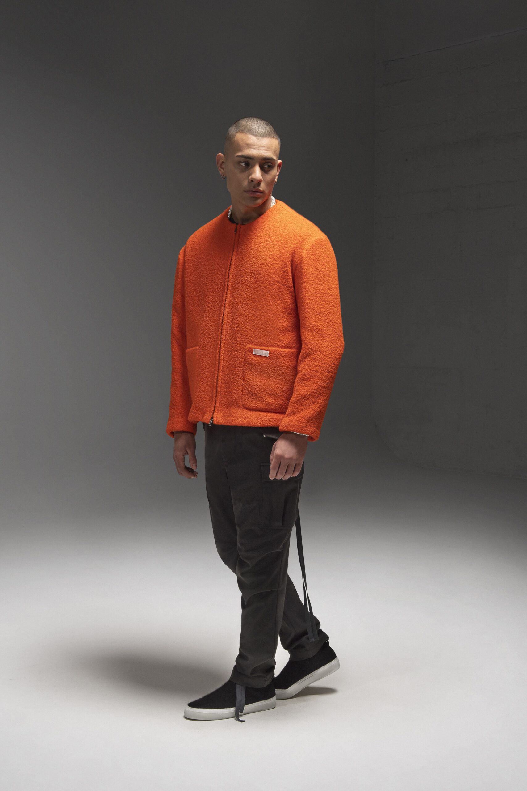 A relaxed orange cotton jacket with long sleeves, paired with black pants and a zippered detail.
