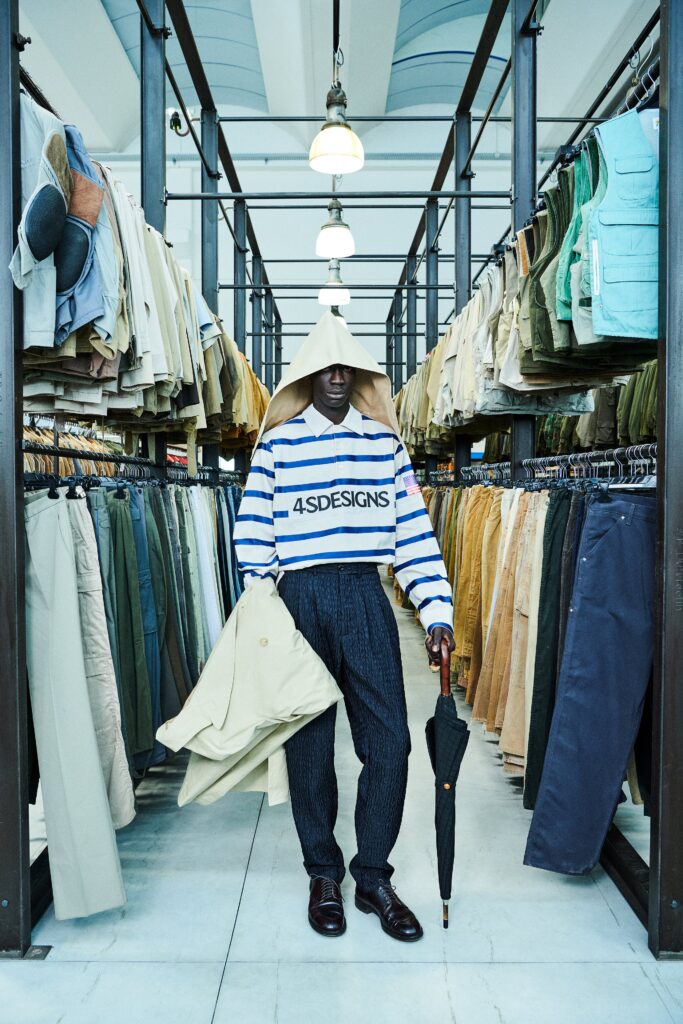 A relaxed beige cotton jacket with long sleeves and a collared design, paired with striped pants.
