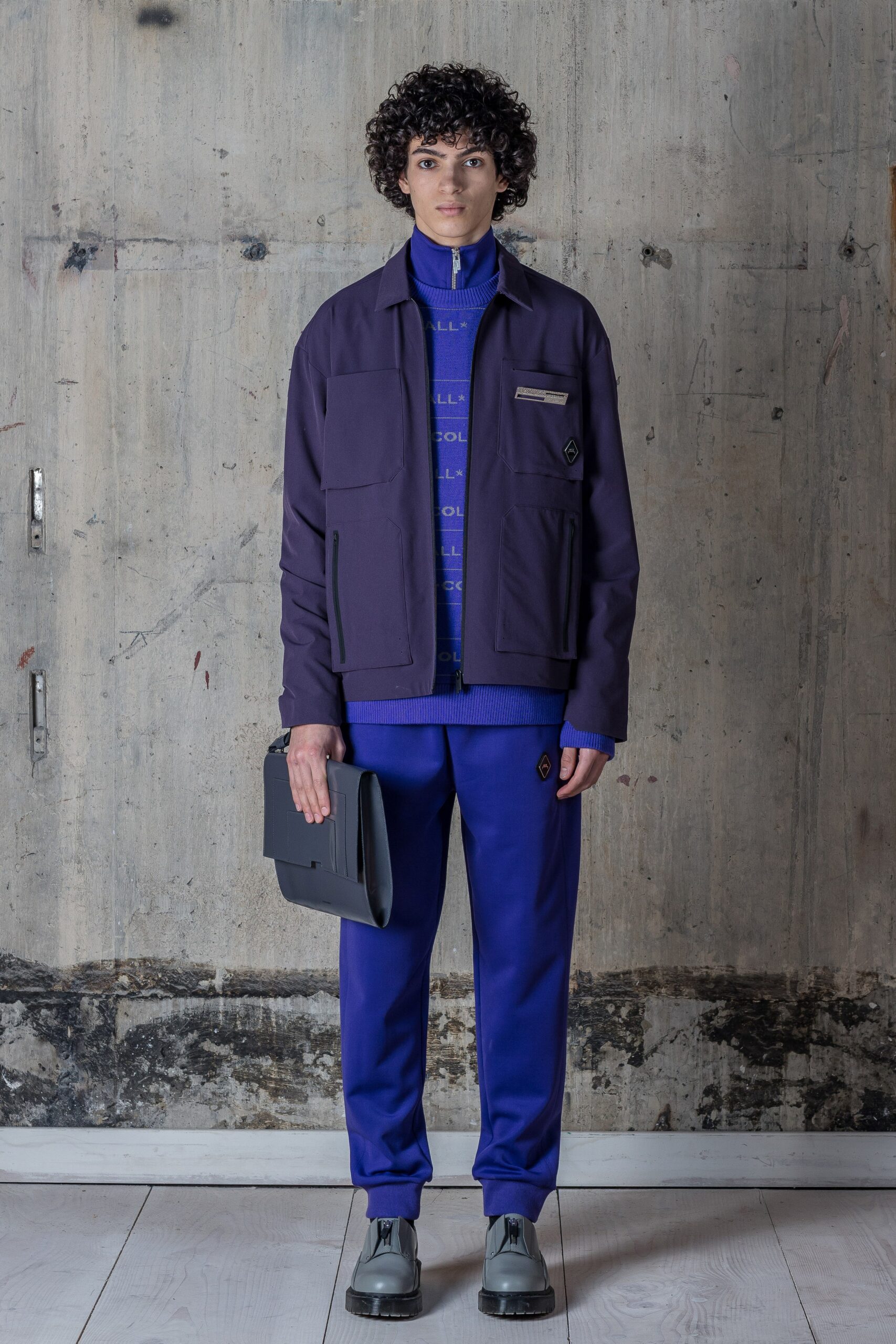 A relaxed purple cotton jacket with long sleeves and a zippered detail, paired with blue pants.