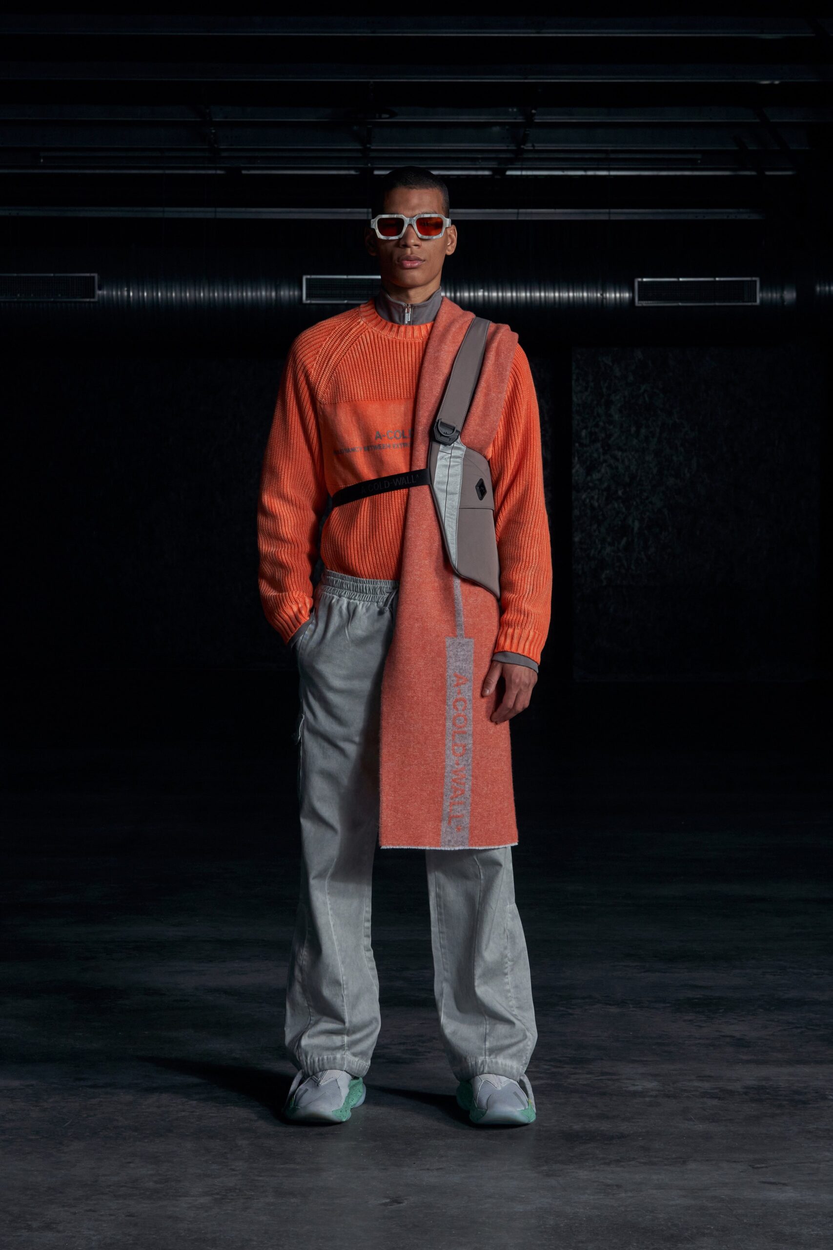 A relaxed orange long-sleeve sweater paired with gray pants featuring a layered design.