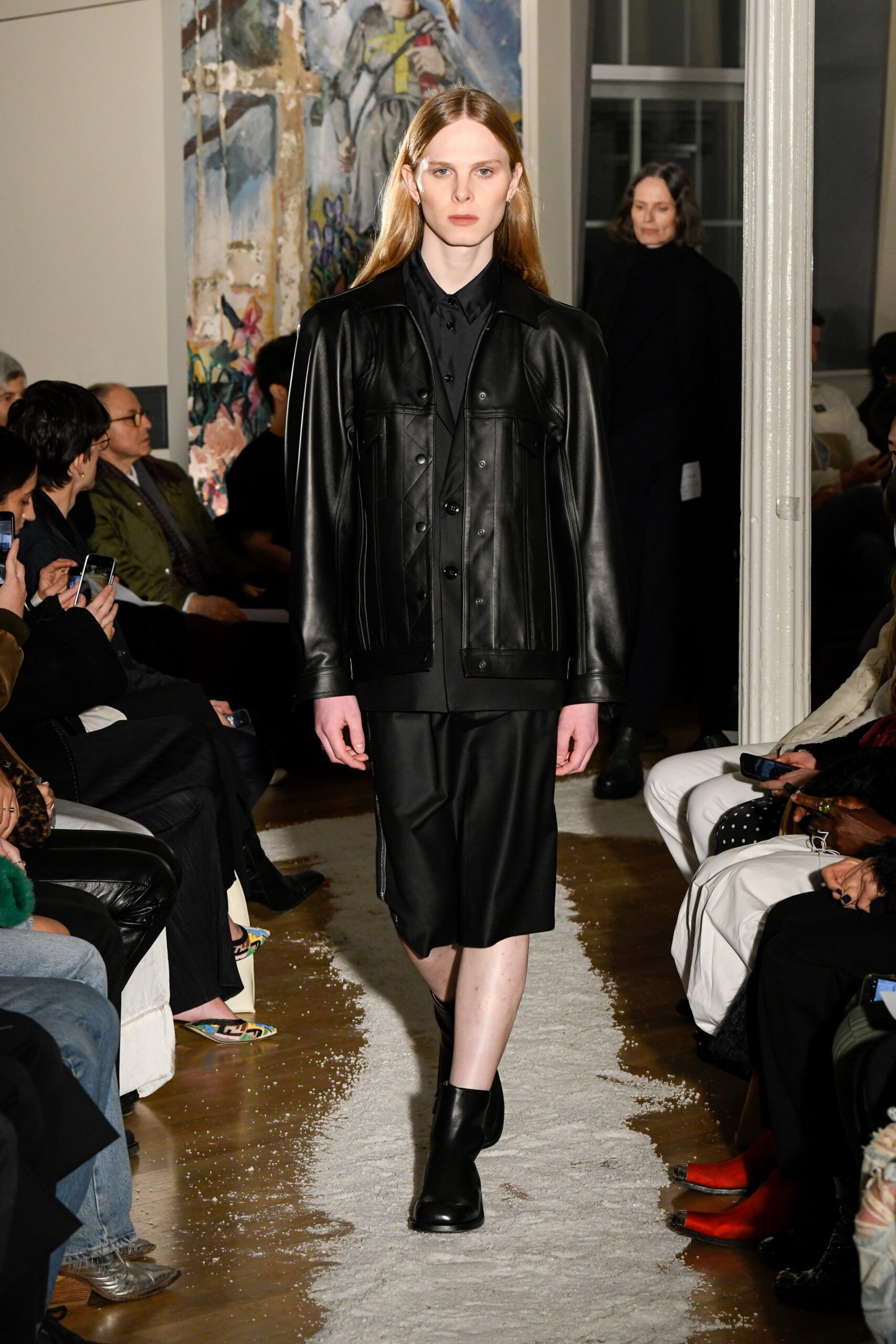 A fitted black leather jacket paired with a matching skirt, showcasing a sleek silhouette.
