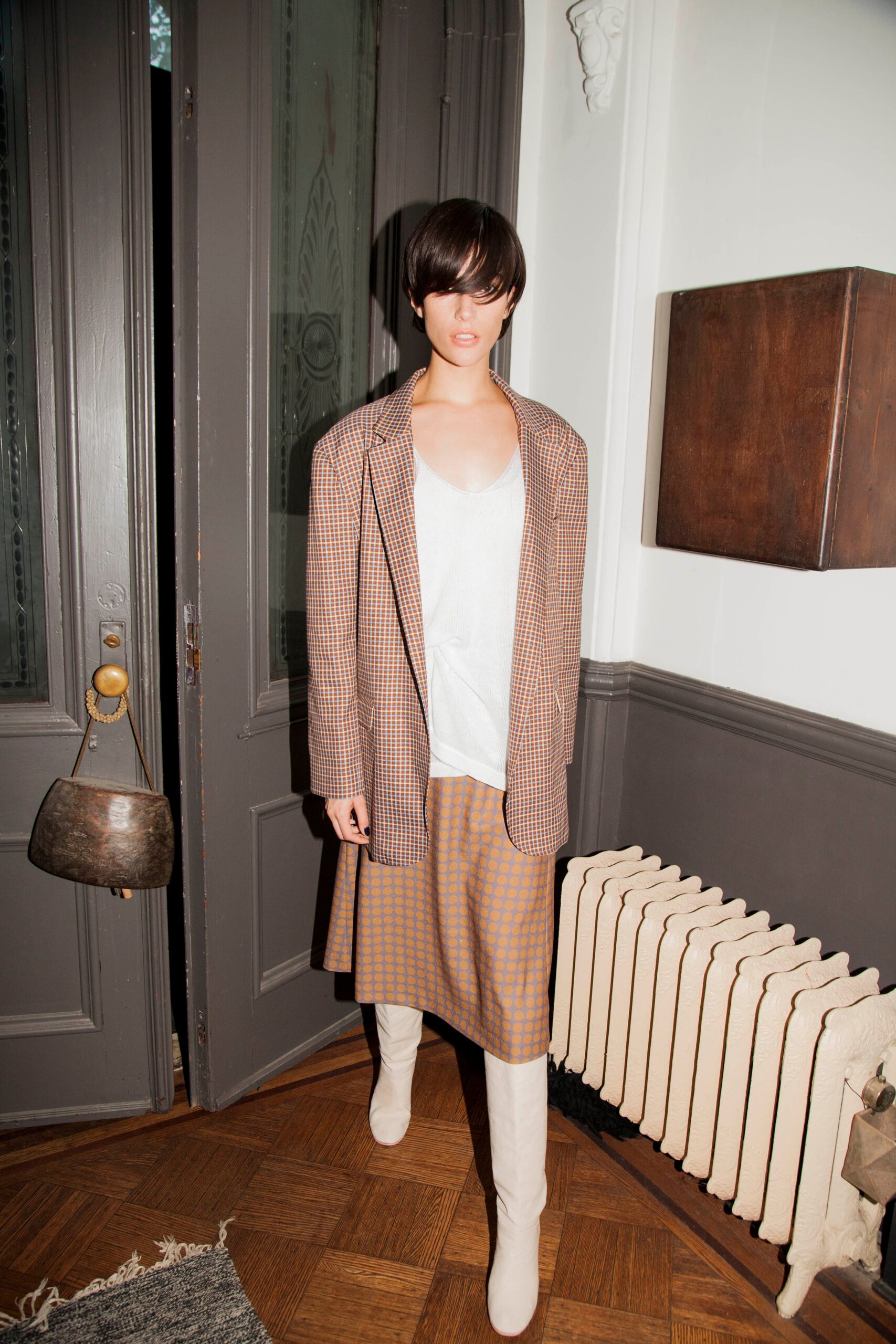 A fitted brown checked blazer paired with a beige skirt, creating a stylish ensemble.