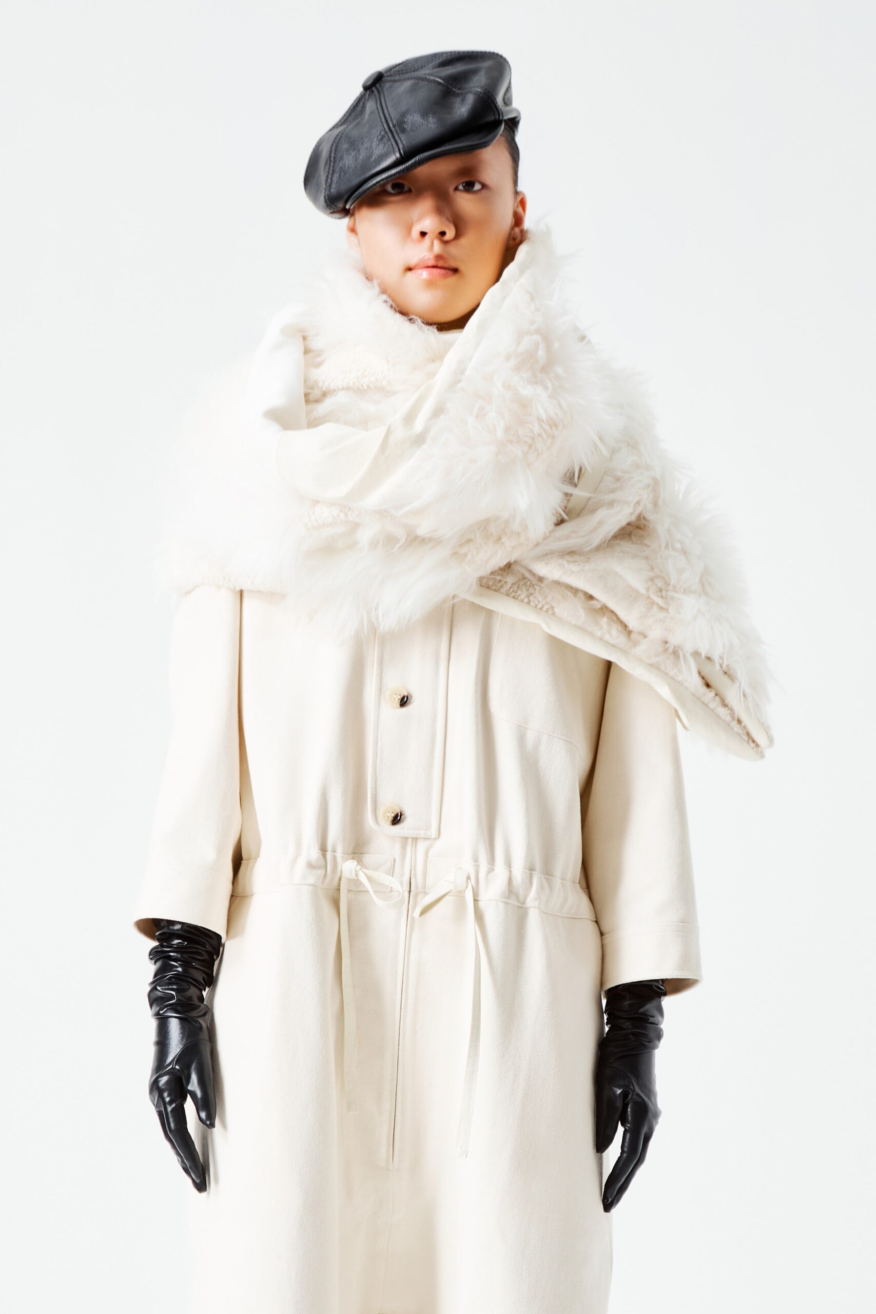 This relaxed coat jumpsuit features a long-sleeve design with a collared neckline, creating an intriguing interplay of structure and softness. The layered fur detail adds a luxurious texture, enhancing the overall silhouette while maintaining an effortless aesthetic.