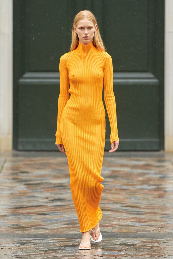 A fitted orange knit dress with a turtleneck and long sleeves, featuring a straight-leg silhouette.