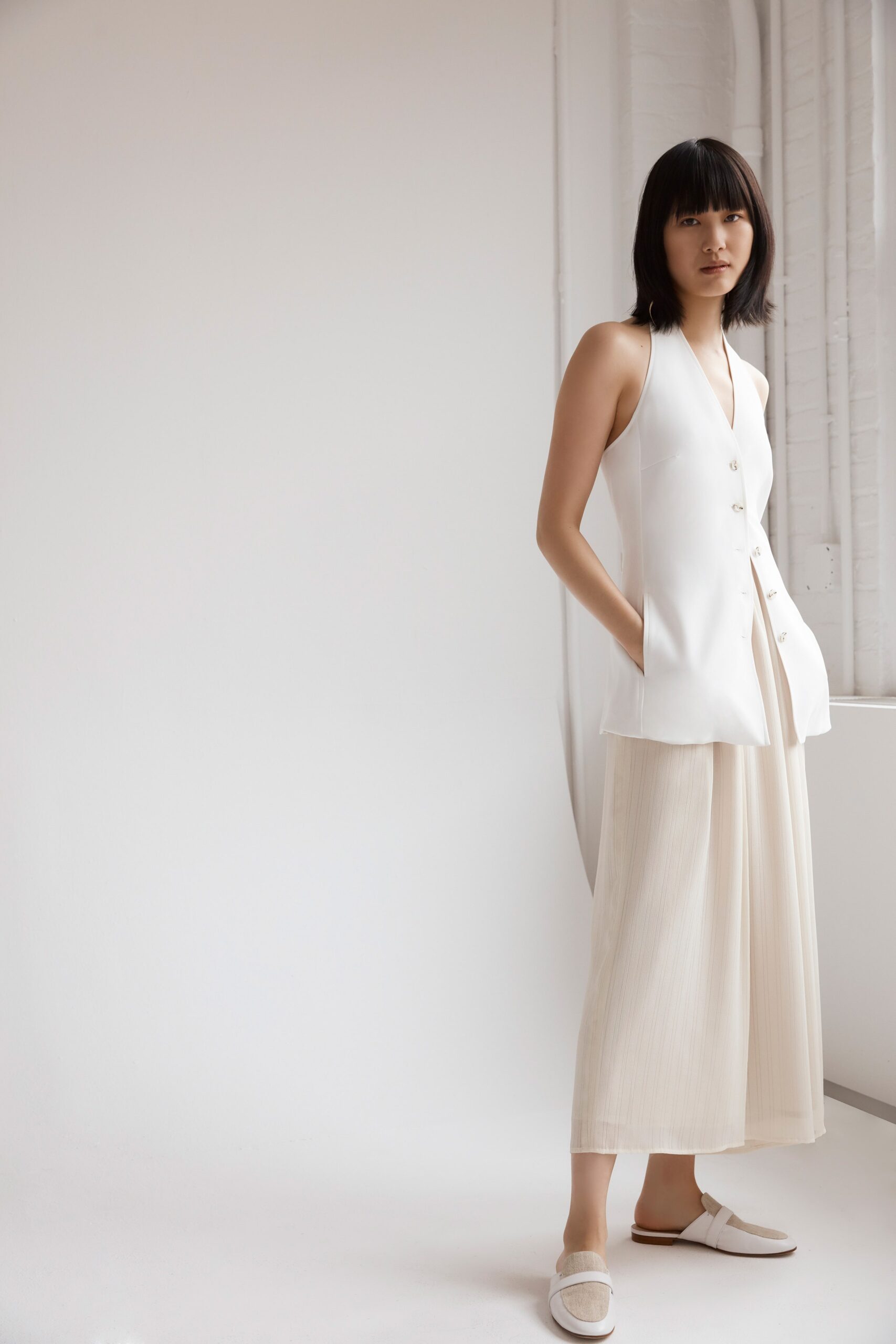 white silk fitted vest and beige pleated pants