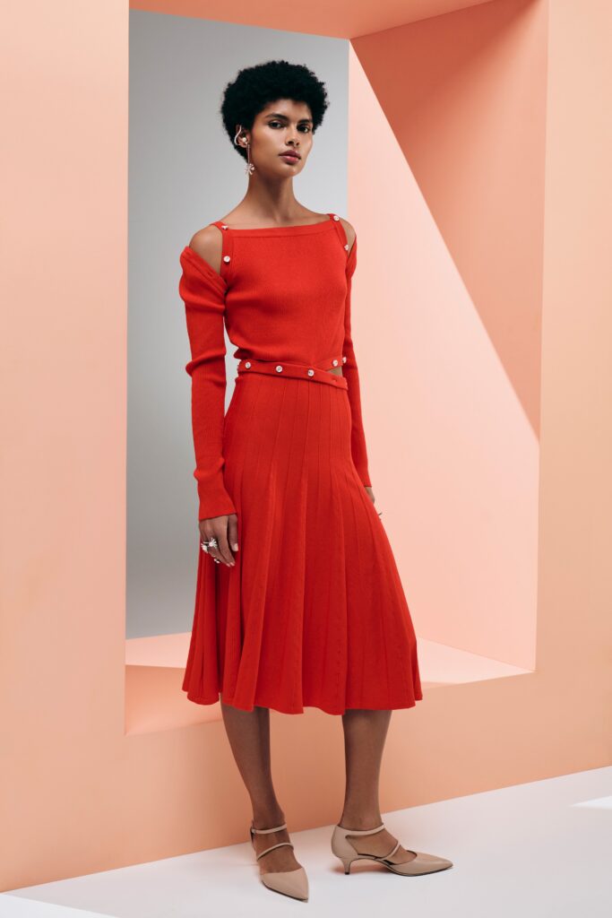 A fitted red knit dress with long sleeves and a pleated design.