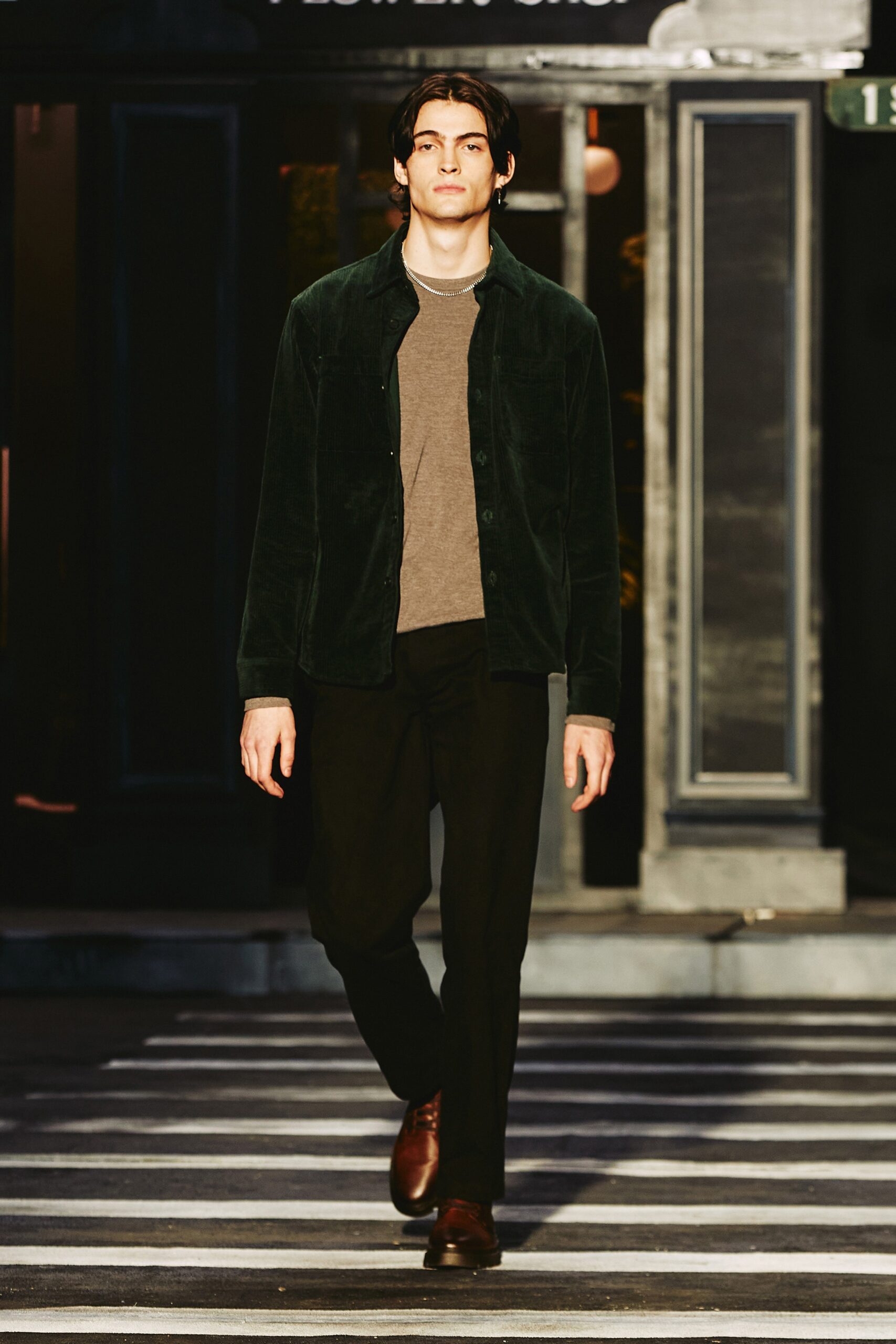 A relaxed green cotton jacket with a collared design paired with black pants.