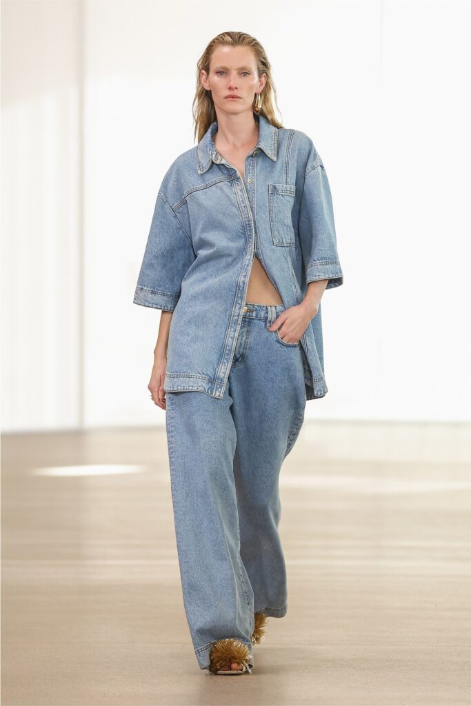 A relaxed fit blue denim shirt with short sleeves paired with wide-leg denim pants.