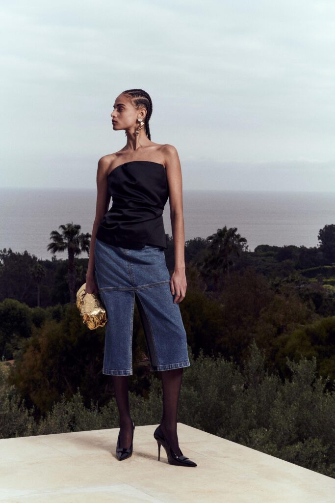 A fitted black silk sleeveless top paired with high-waisted blue denim wide-leg pants.