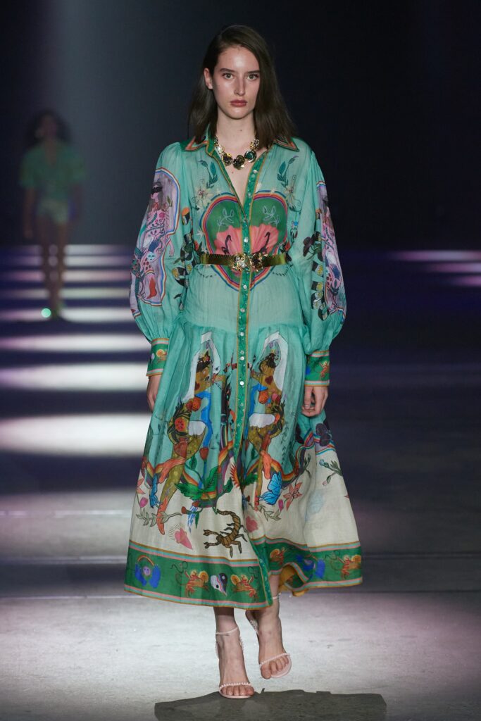 A relaxed green cotton dress with long sleeves, a collared neckline, and vibrant printed details.