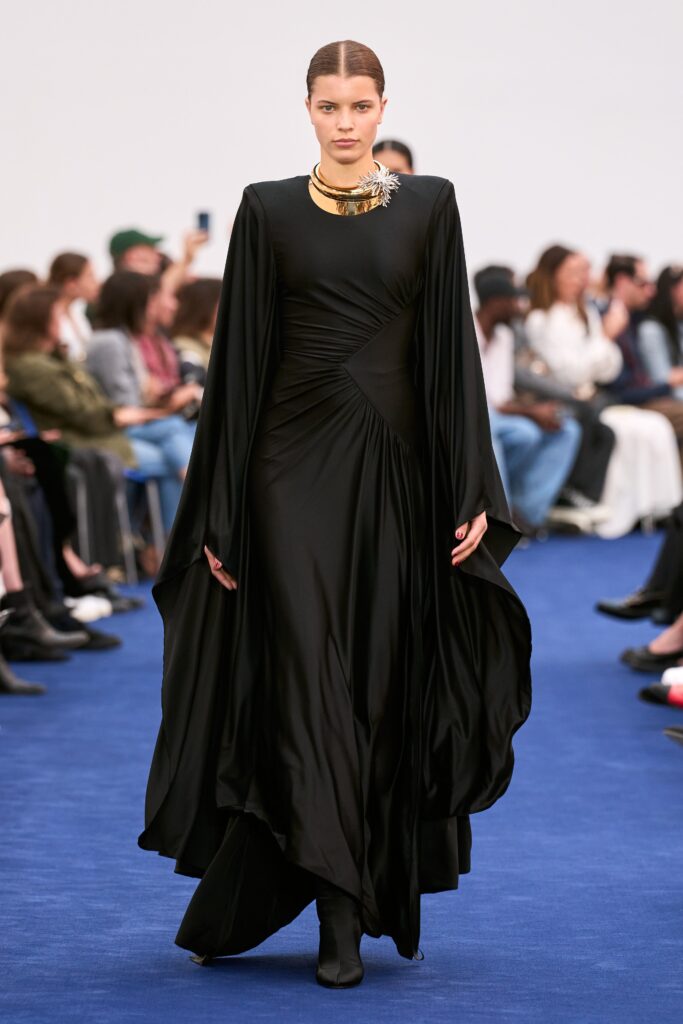 A fitted black silk dress with long sleeves and a draped design detail.