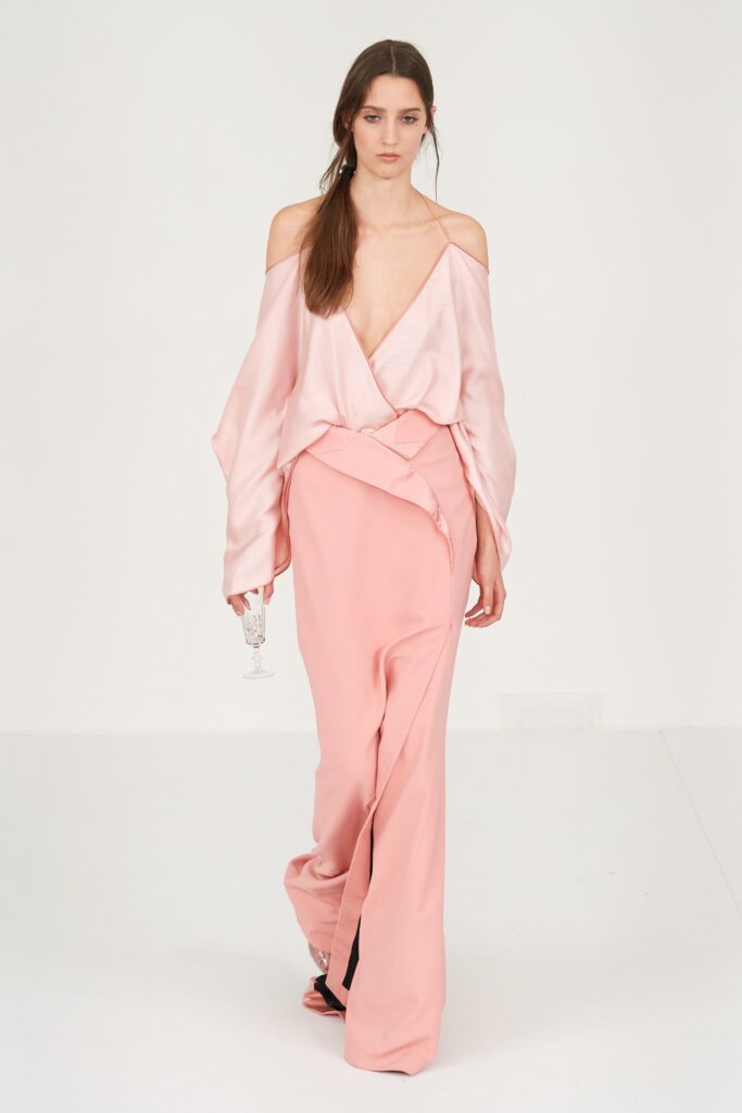 A fitted pink silk sleeveless dress with a V-neckline and asymmetric design.