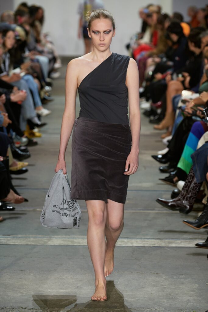 A fitted black cotton dress with an asymmetric design and pencil silhouette.