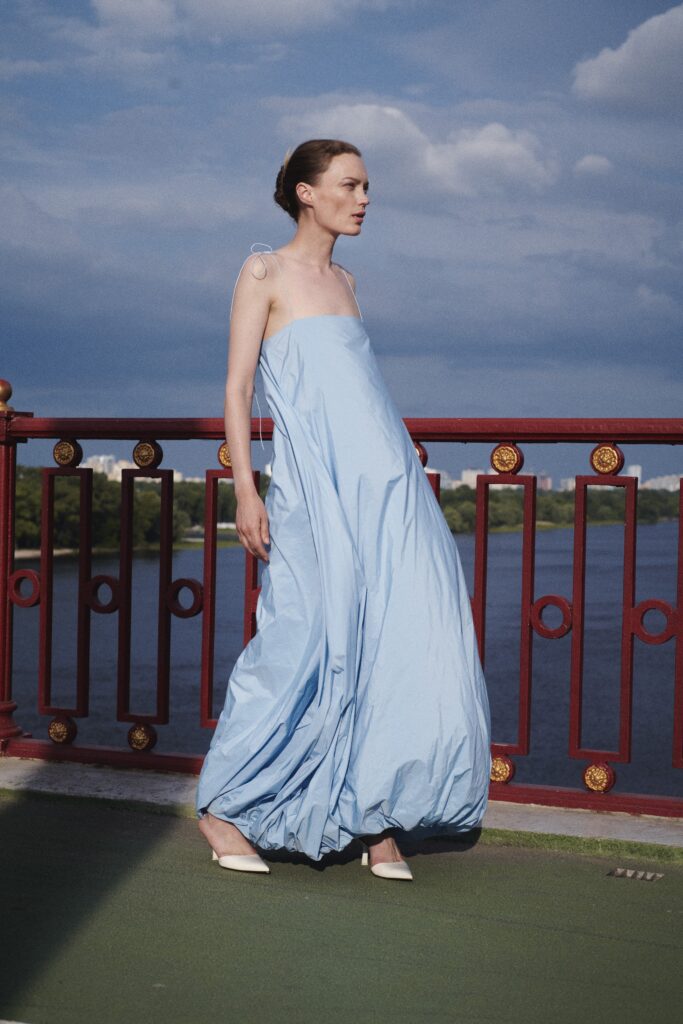 A relaxed blue cotton sleeveless dress with a high neckline and tiered design.