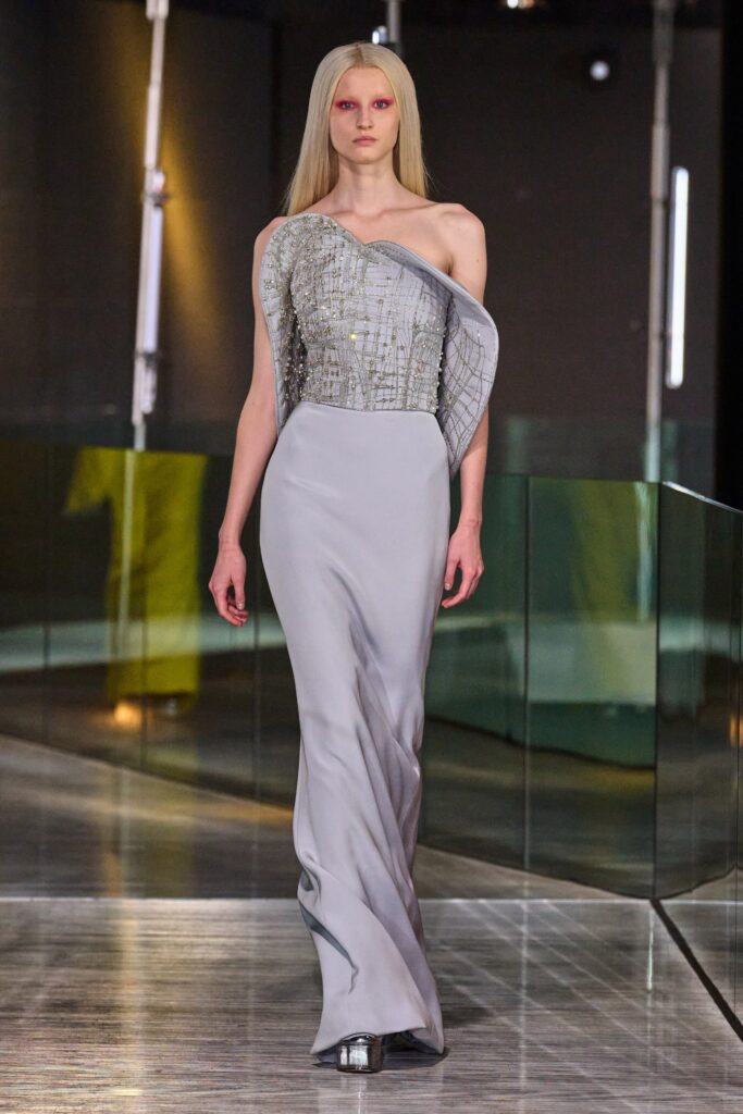 A fitted gray silk gown with an asymmetric design and sleeveless high-neck construction.