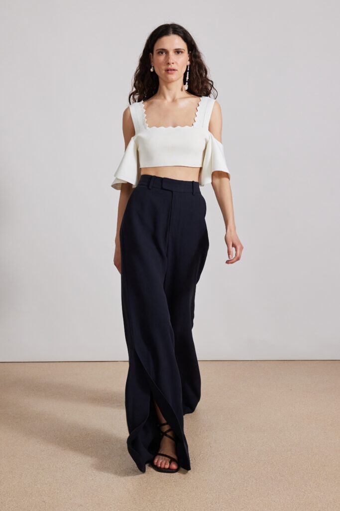 A fitted white top with short sleeves paired with flared navy pants.