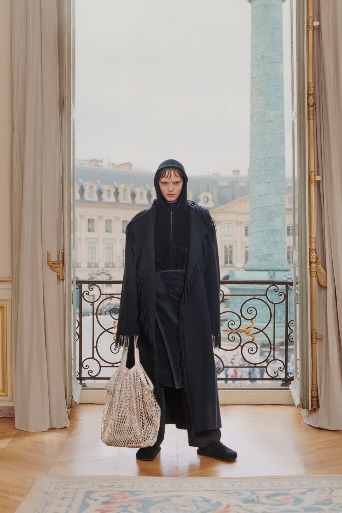 A relaxed black wool coat with a hood and fringed details, perfect for layering.