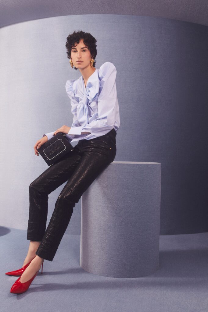 A fitted blue ruffled blouse with long sleeves paired with fitted black leather pants.
