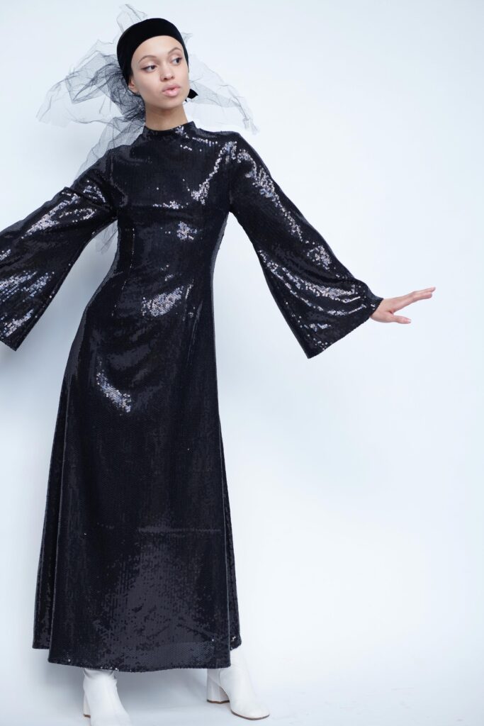 A fitted black sequin maxi dress with long sleeves and a high neckline.