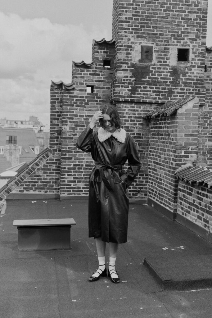 A fitted black leather coat with a collared neckline and belted detail.