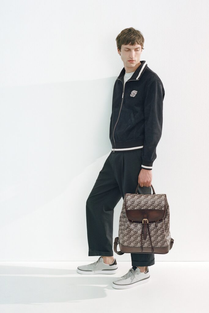 A relaxed black cotton jacket with long sleeves and a collared neckline paired with gray pants.