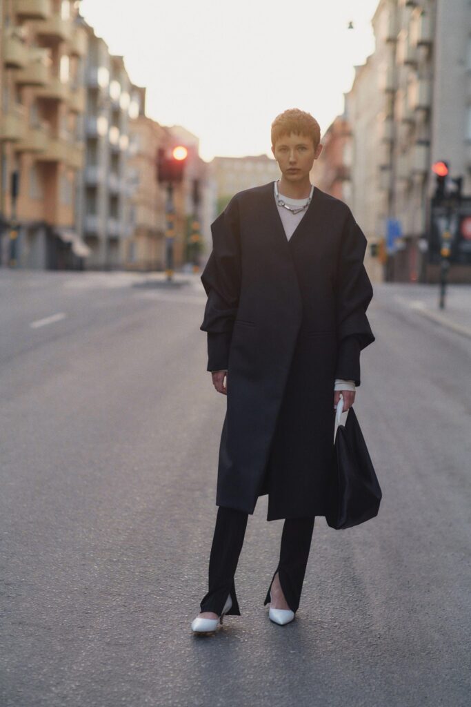 A relaxed black wool coat with long sleeves and an asymmetric design paired with matching pants.