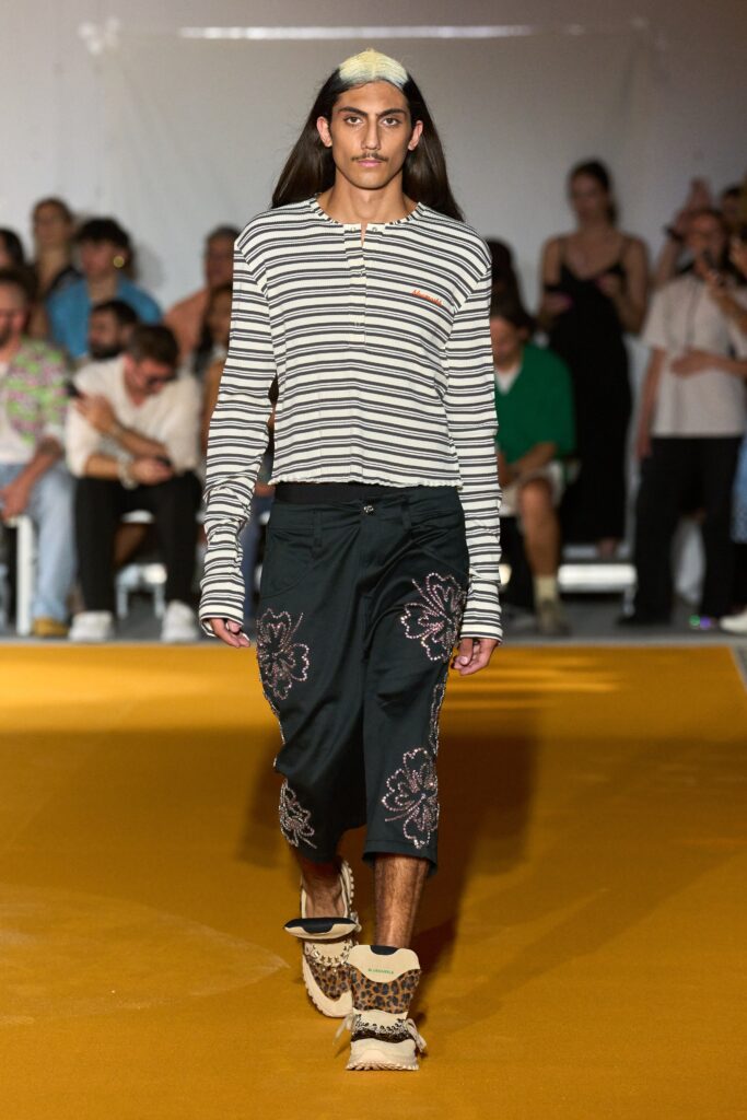 A relaxed black and white striped long-sleeve shirt paired with flared black pants.