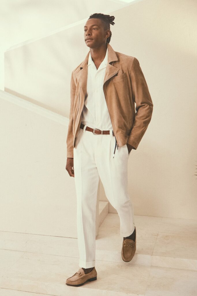 A fitted beige suede jacket paired with white cotton pants, featuring a collared design.