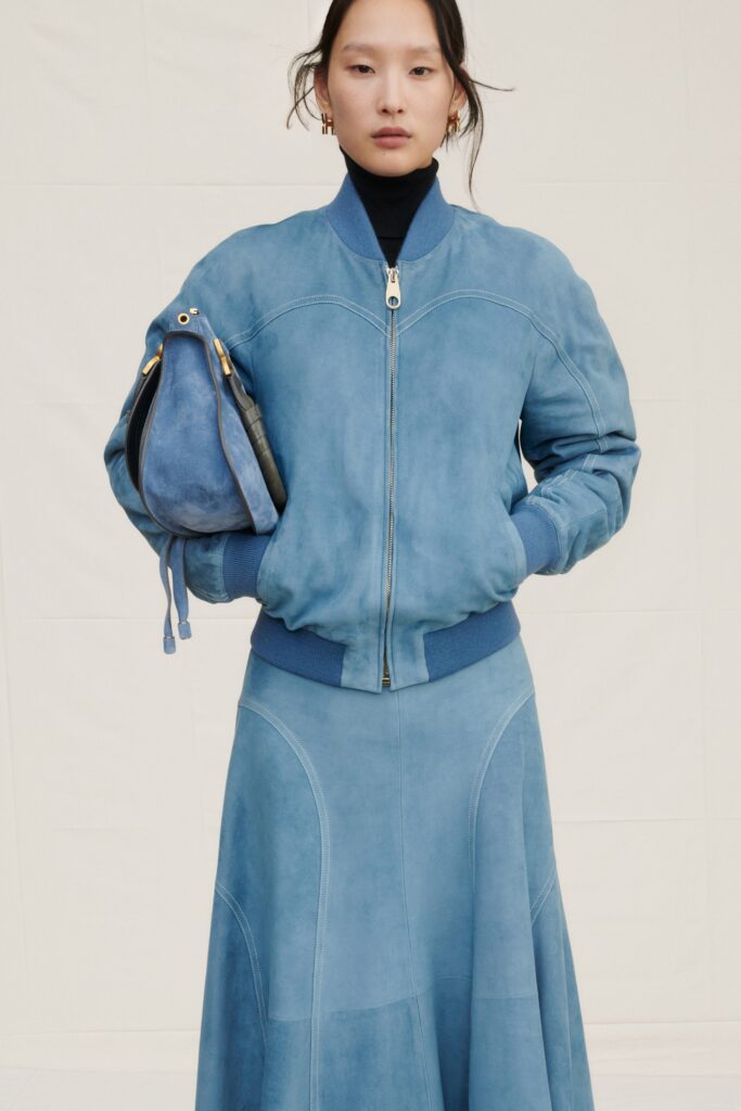 A fitted blue leather jacket with a collared neckline paired with a flared leather skirt.