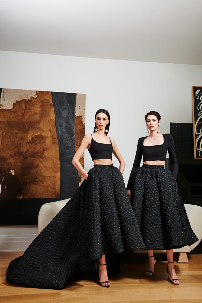 A fitted black silk sleeveless dress with a high neckline and tiered silhouette.