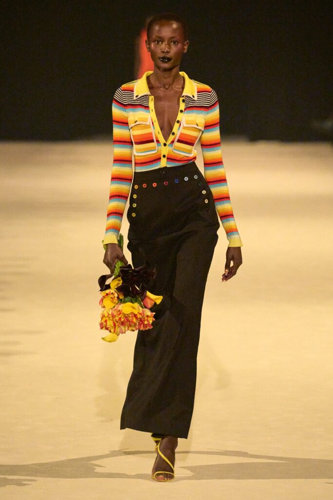 A fitted multicolor striped long-sleeve top paired with high-waisted black pants.