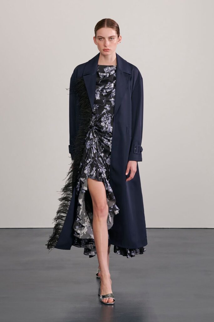 A fitted black and blue dress with a long coat featuring an asymmetric and flared design.