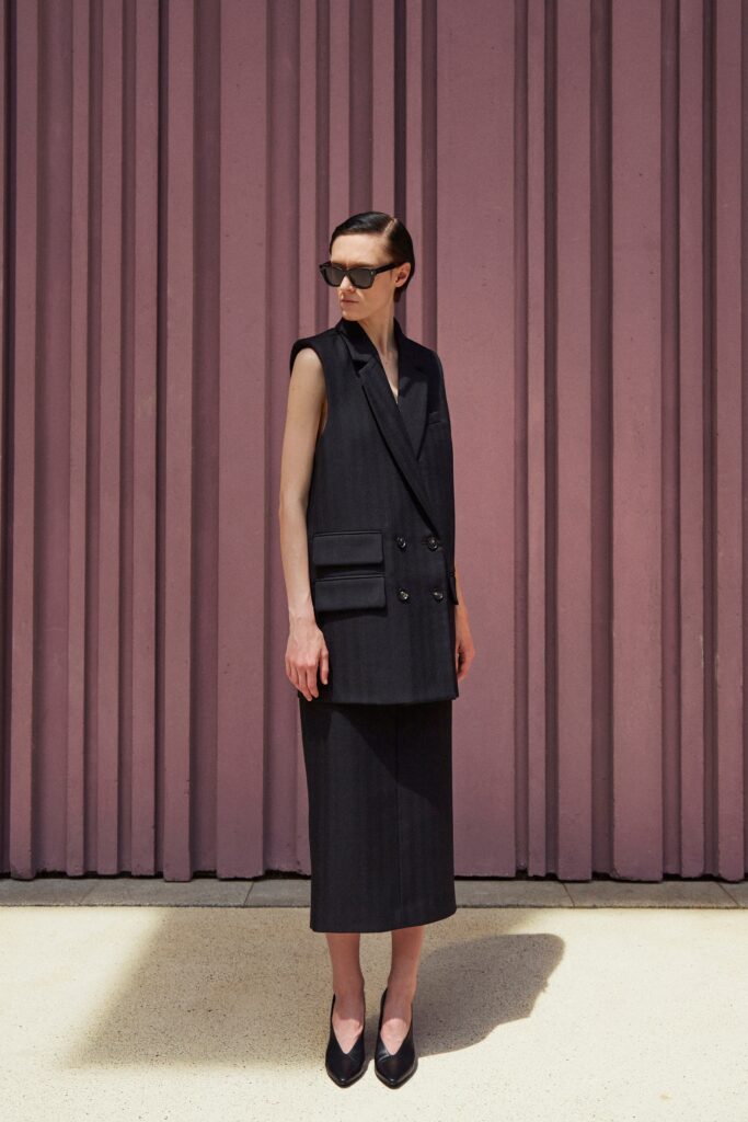 A fitted black sleeveless vest with a collared design paired with a pencil skirt.