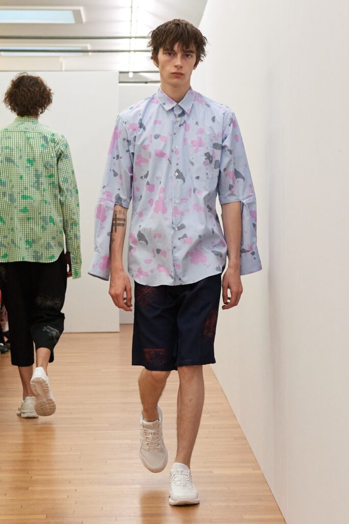 A relaxed blue and white printed shirt with long sleeves and collared design paired with shorts.