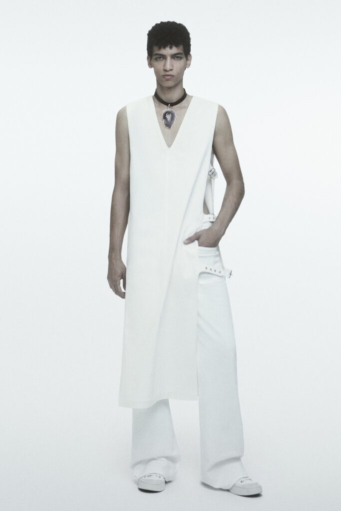 A relaxed white sleeveless dress with a V-neckline paired with straight-leg pants.