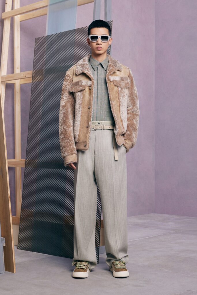 An oversized beige fur jacket paired with gray cotton pants for a stylish look.