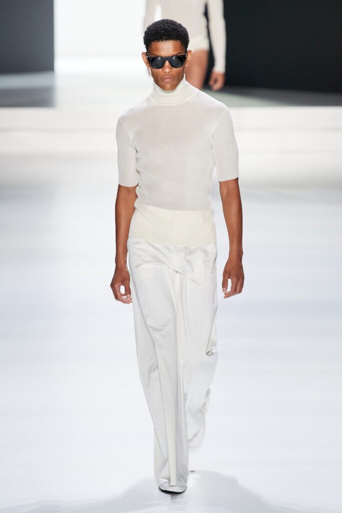 A fitted white short-sleeve top with a turtleneck paired with wide-leg pants.
