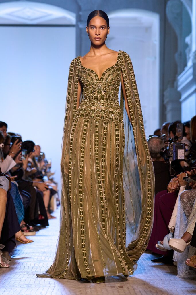 A fitted green silk gown with long sleeves, a V-neckline, and intricate embroidery.