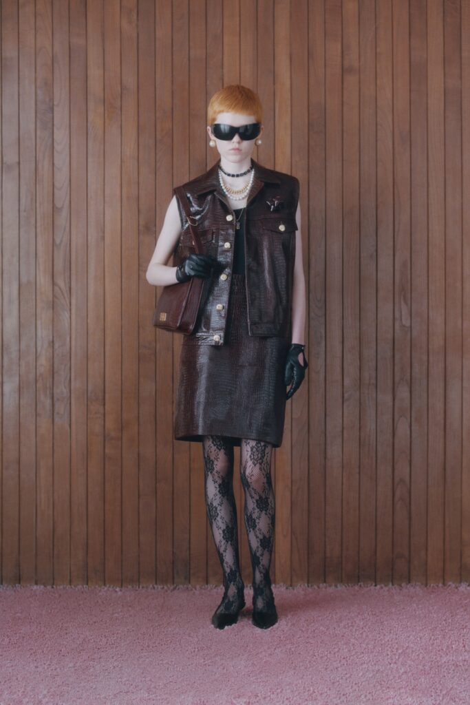 A fitted black leather dress with a collared sleeveless jacket, featuring a pencil silhouette.