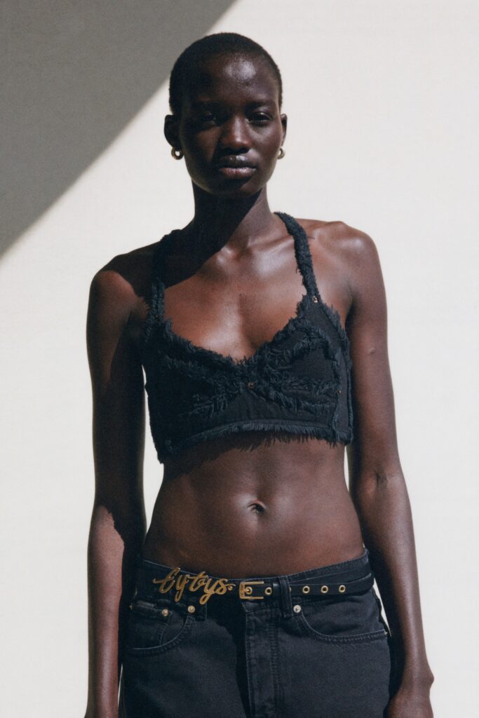 A fitted black sleeveless top with fringed details paired with fitted black pants.